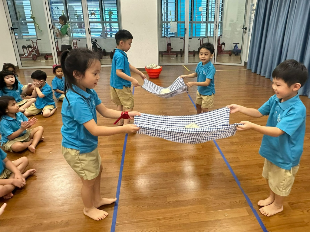 Children work in pairs to complete a teamwork challenge, developing communication, cooperation and problem-solving skills through play.