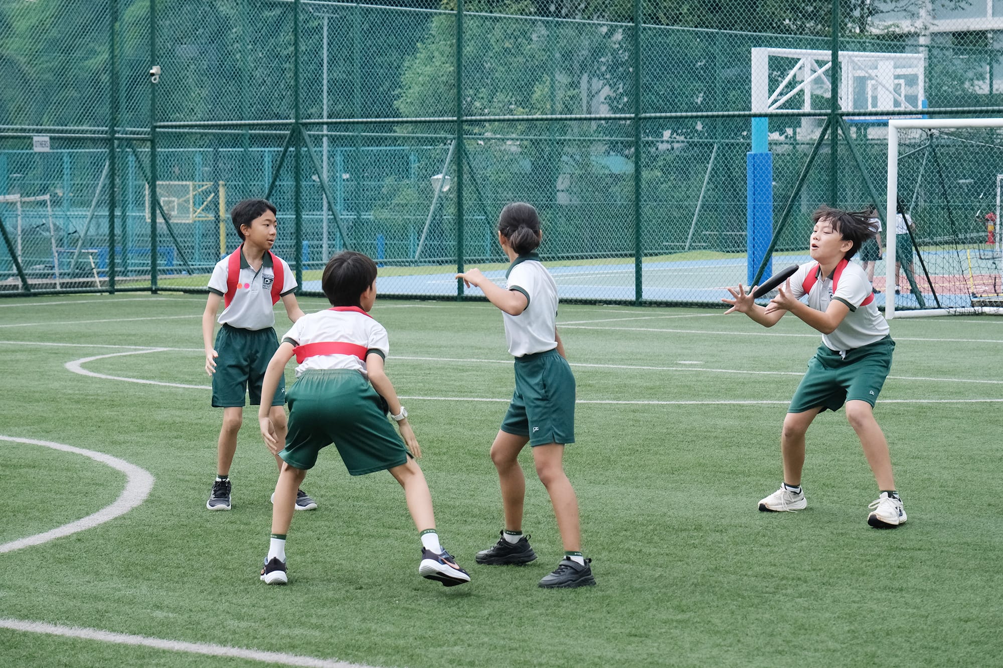 Students work together during an Ultimate Frisbee match, with one player catching the disc while teammates spread out and communicate to prepare for the next pass.