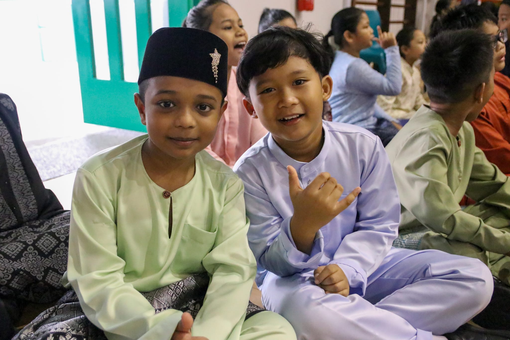 Two students in traditional Malay attire smile for the camera while taking part in the school's Hari Raya celebration.