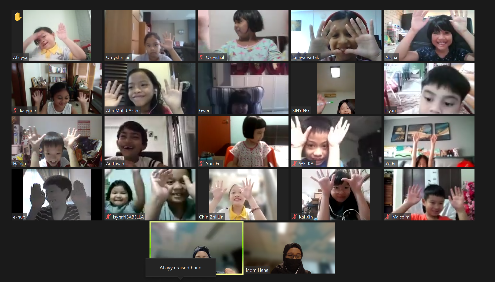 A video call grid showing about 17 children waving their hands, with name labels and a teacher visible at the bottom.