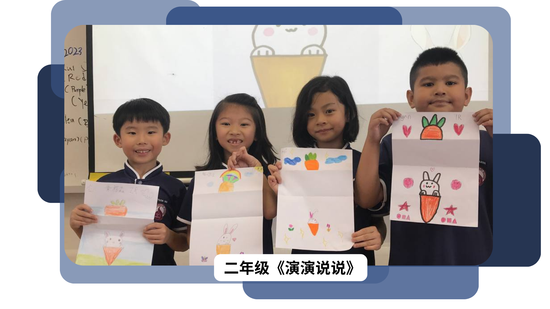 Four young students in uniforms smile while holding up drawings of rabbits and carrots in a classroom.