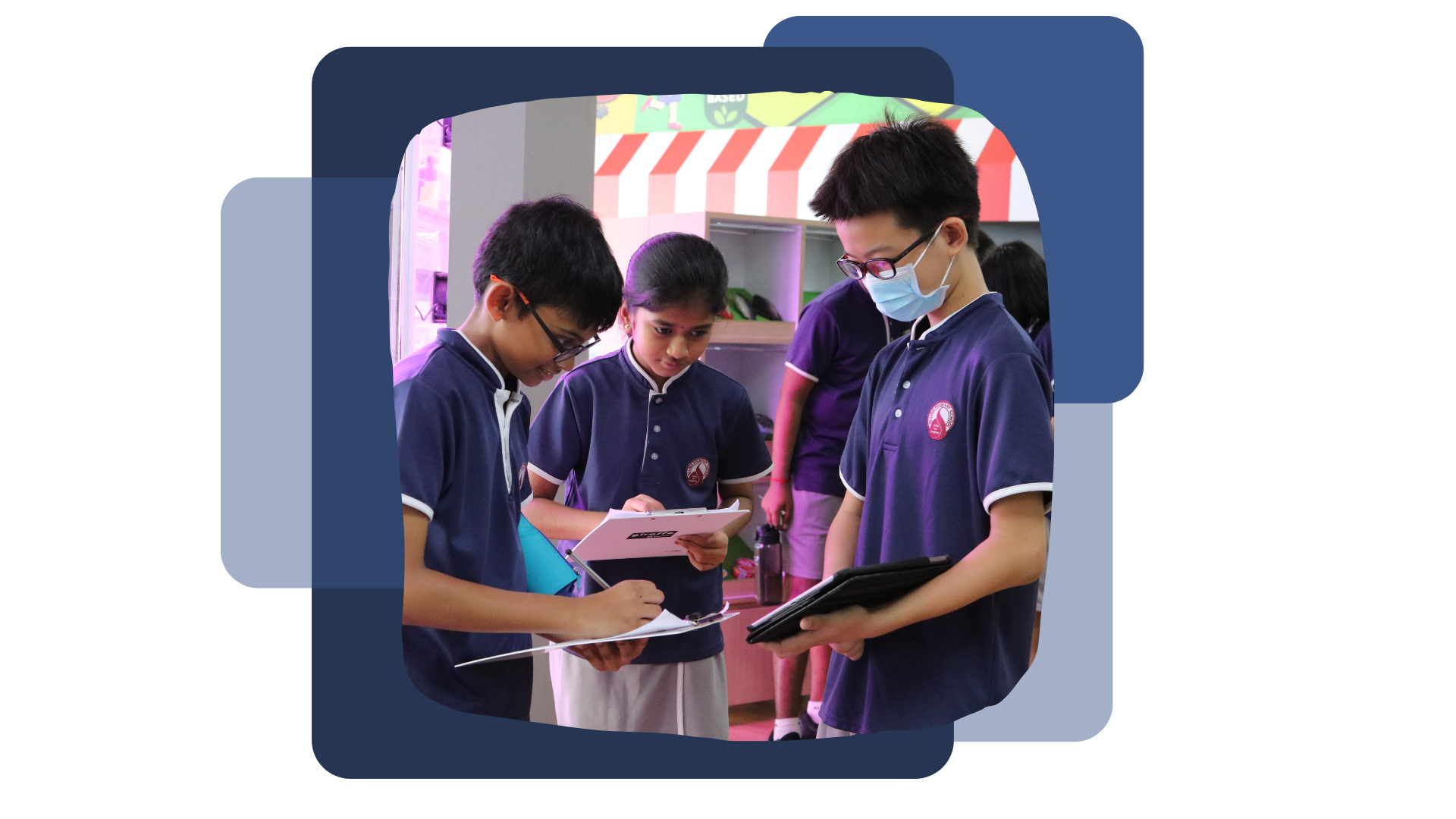 3 students in school uniform. 2 boys with glasses, 1 with mask & 1 girl. All 3 of them are holding to a clipboard.