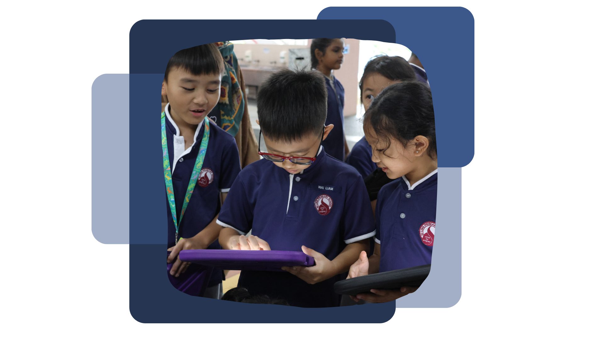 Three young students in navy school uniforms gather around a tablet, with one boy wearing red glasses tapping the screen.