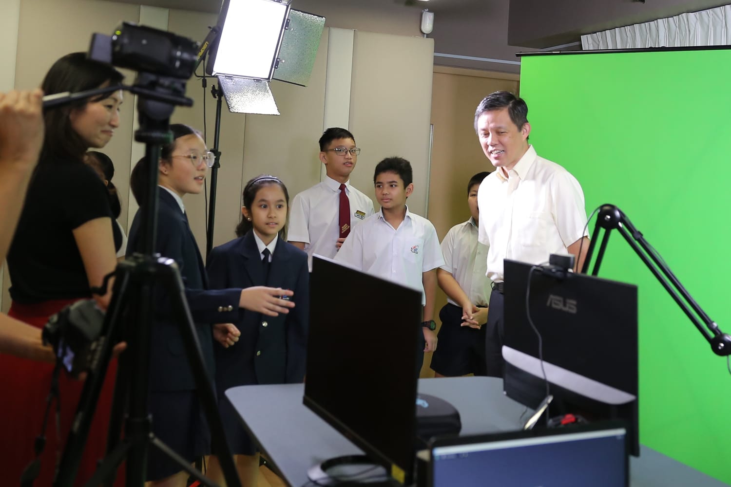 Minister Chan touring the school's green screen studio while students explain the media production setup.