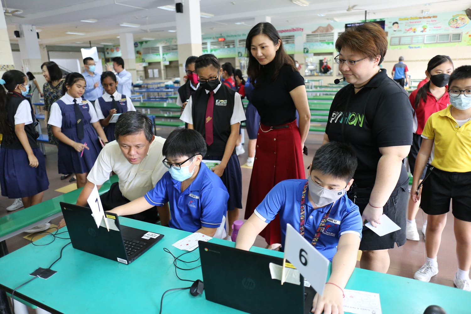 Minister Chan observing students as they demonstrate a Science and Technology Week activity on laptops.