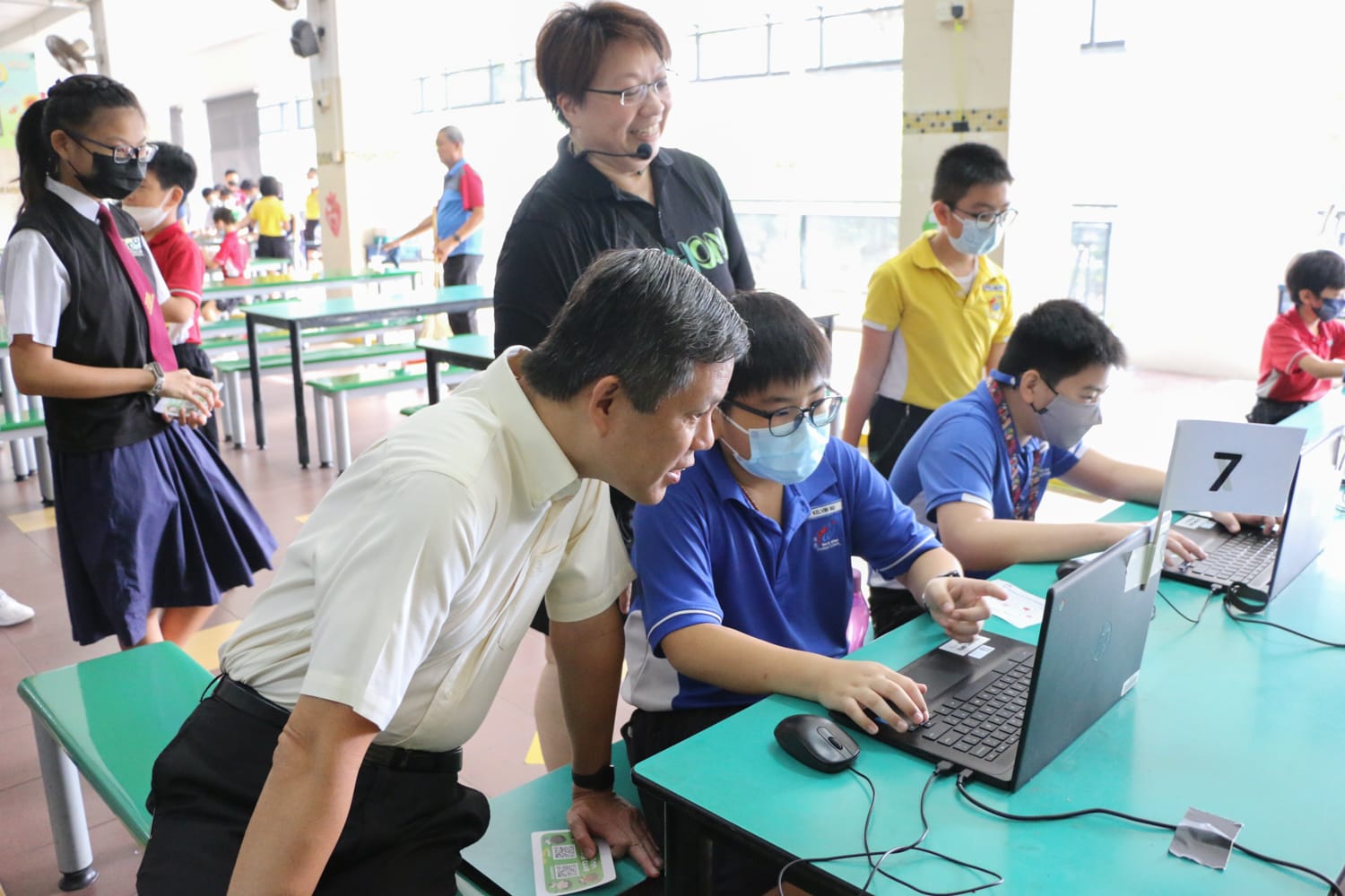 Minister Chan observing students demonstrating their Science and Technology Week projects on laptops.