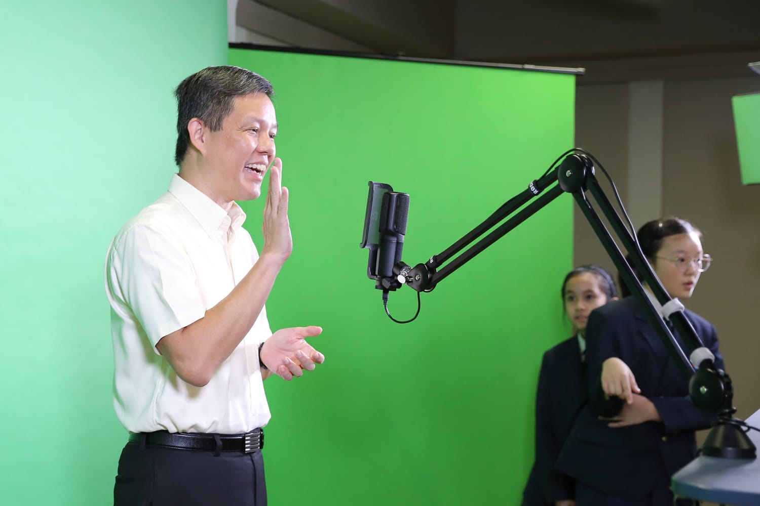 Minister Chan standing in the school's green screen studio beside a studio microphone during his visit to Teck Whye Primary School.