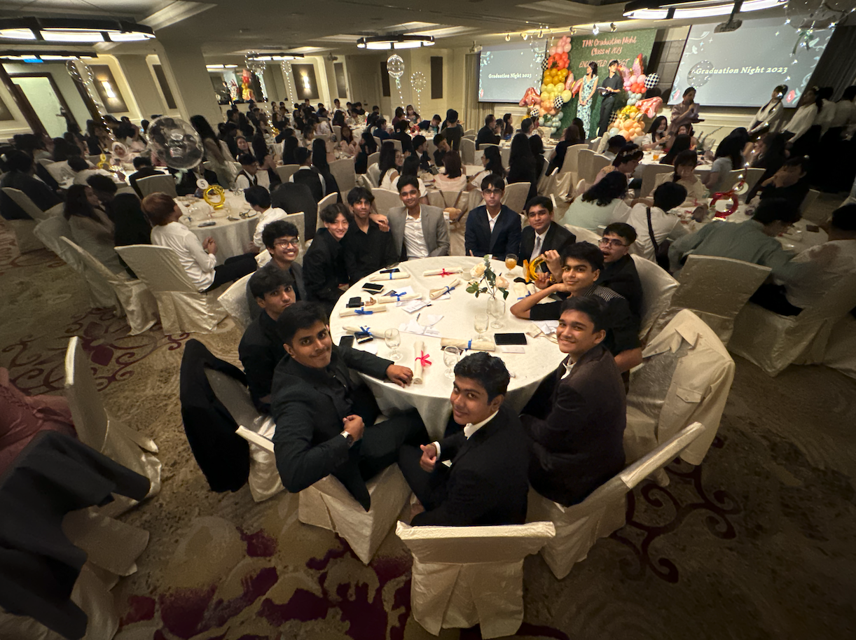 A group of young people in formal attire sit around a round table at a 2023 graduation night banquet.