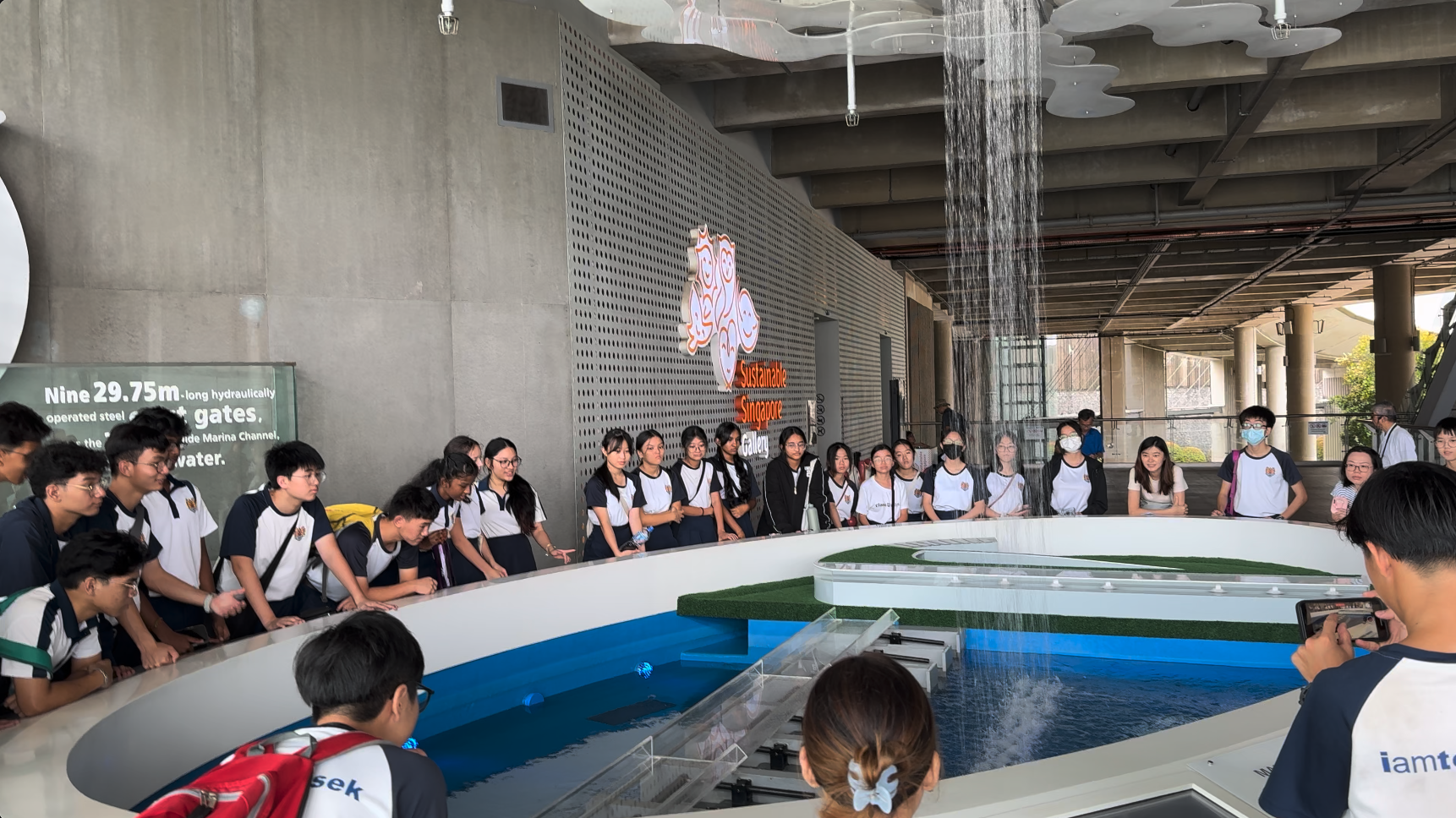 Students in uniform gather around a water feature display at the Sustainable Singapore Gallery.