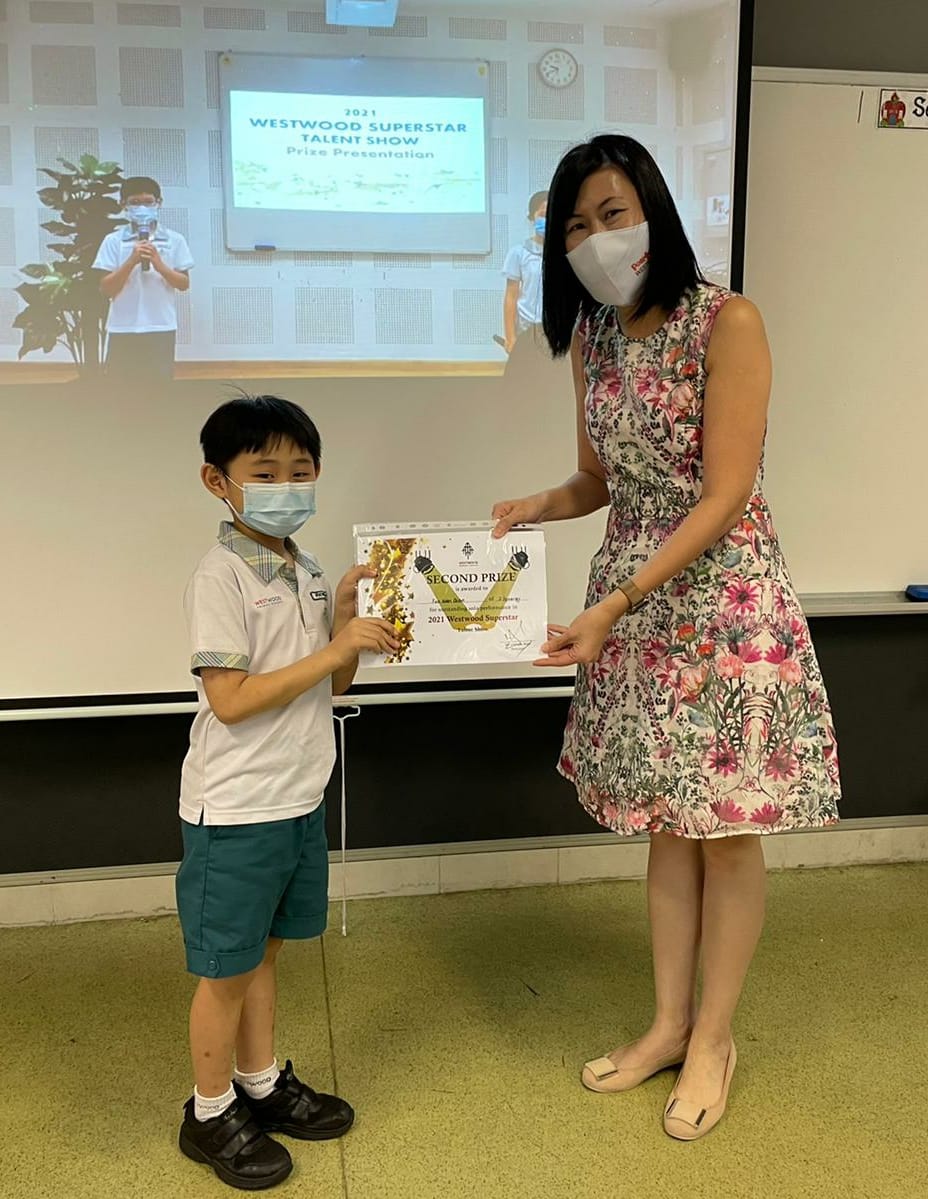 A woman and young boy both wearing masks hold a Second Prize certificate at the 2021 Westwood Superstar Talent Show.
