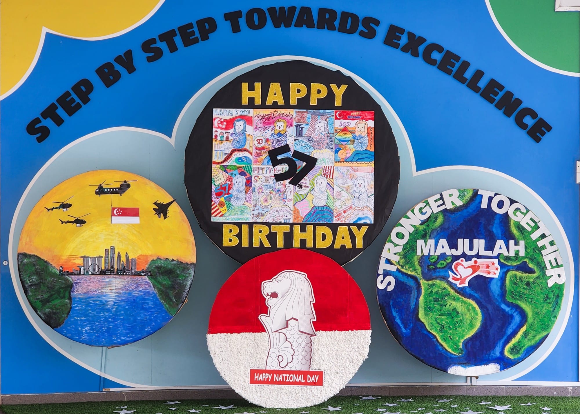Colorful Singapore National Day display with four circular artworks reading Happy Birthday SG57, Majulah, and Happy National Day.