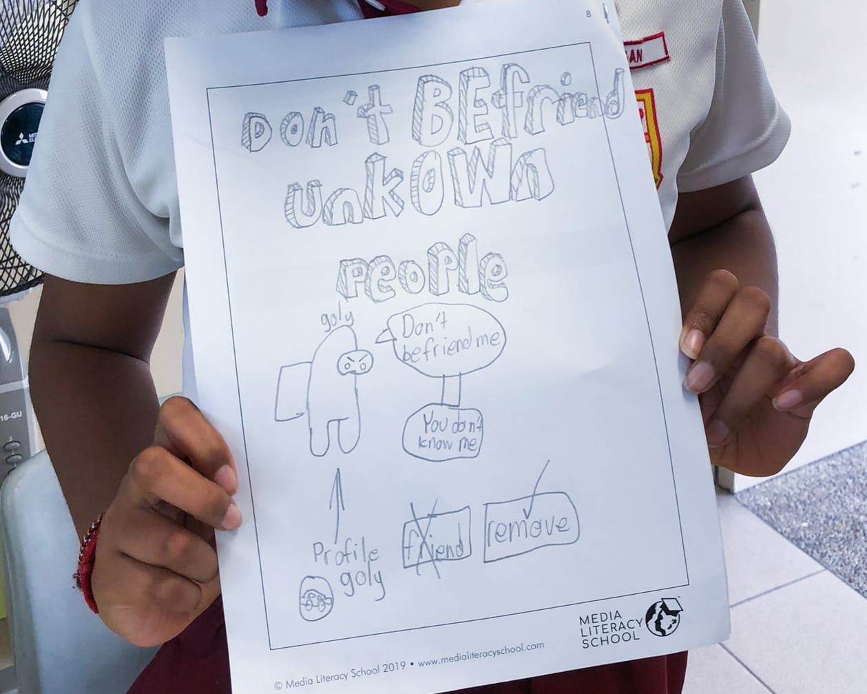 A child holds a hand-drawn poster reading "Don't Befriend Unknown People" with sketched figures and safety tips.