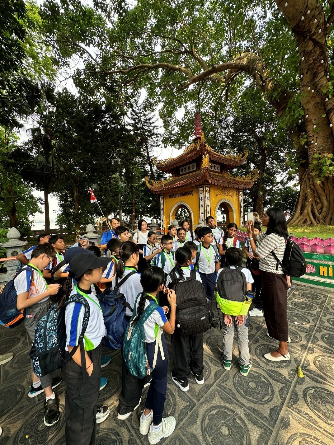 Students from Woodlands Ring Primary School gather around a Principal for a guided explanation at Tran Quoc Pagoda, one of Hanoi's oldest Buddhist temples, during their Overseas Cultural Immersion Programme