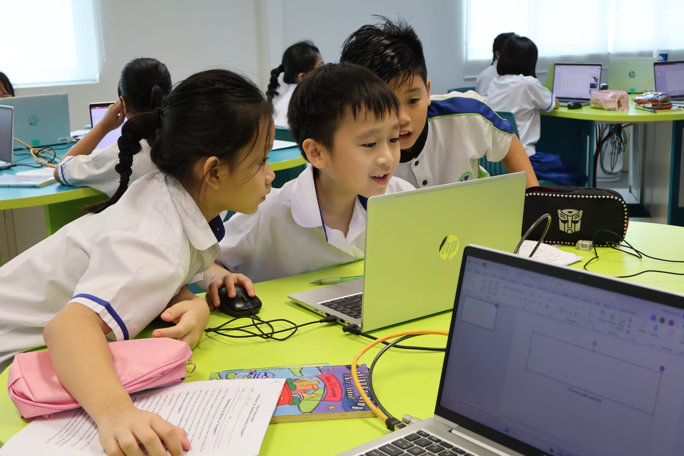 Primary school students in school uniforms collaborating on an HP laptop during an ICT lesson
