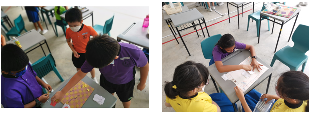 Children in school uniforms and masks work on board activities at desks in a classroom setting.