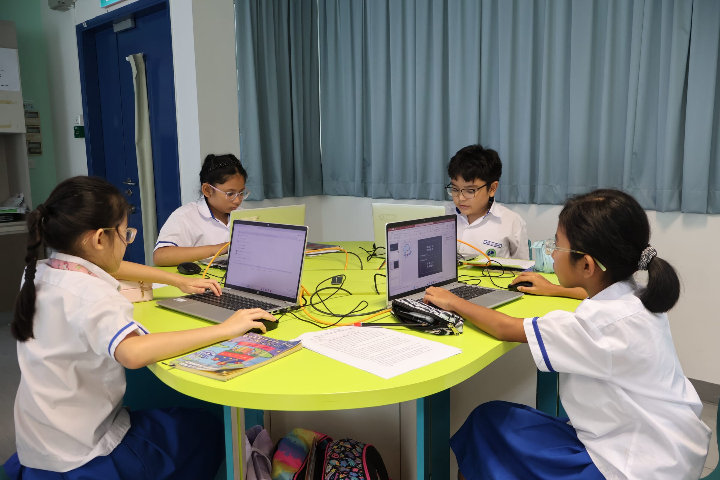 students in school uniforms collaborating on an HP laptop during an ICT lesson