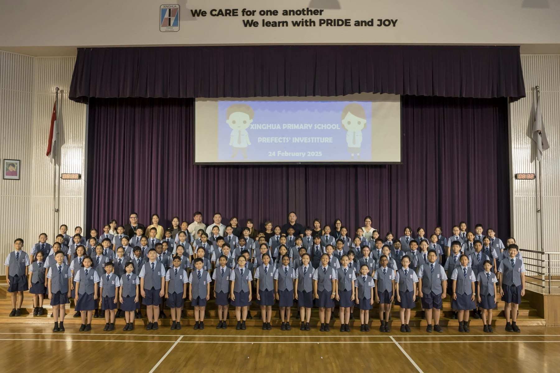 Large group of uniformed students and teachers pose in a school hall at Xinghua Primary School Prefects Investiture 2025.