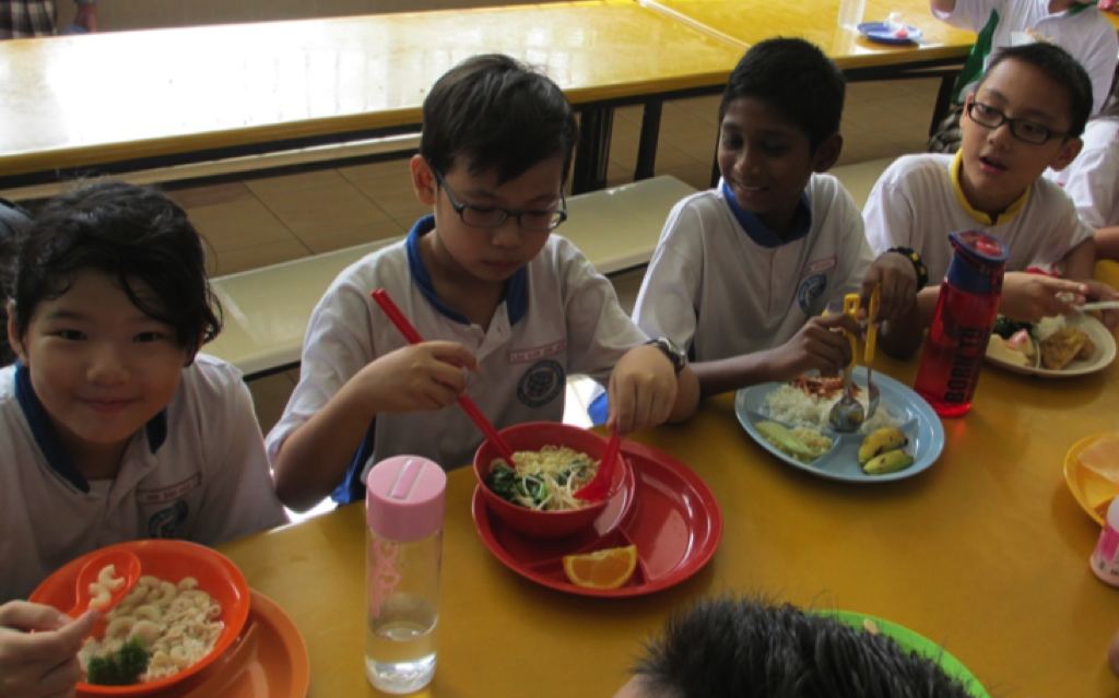 Students eating healthy set meals together in the school canteen.