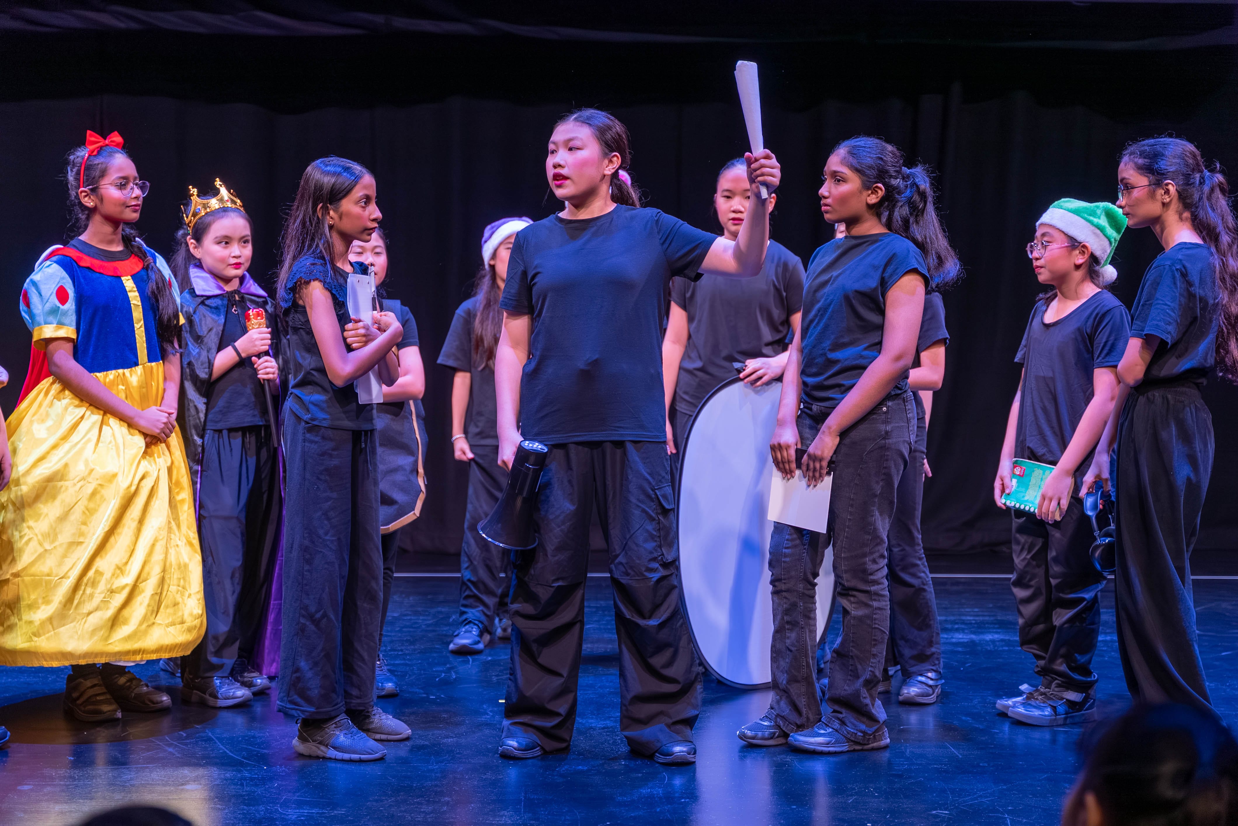 Students performing a drama scene on stage during a school theatre production.