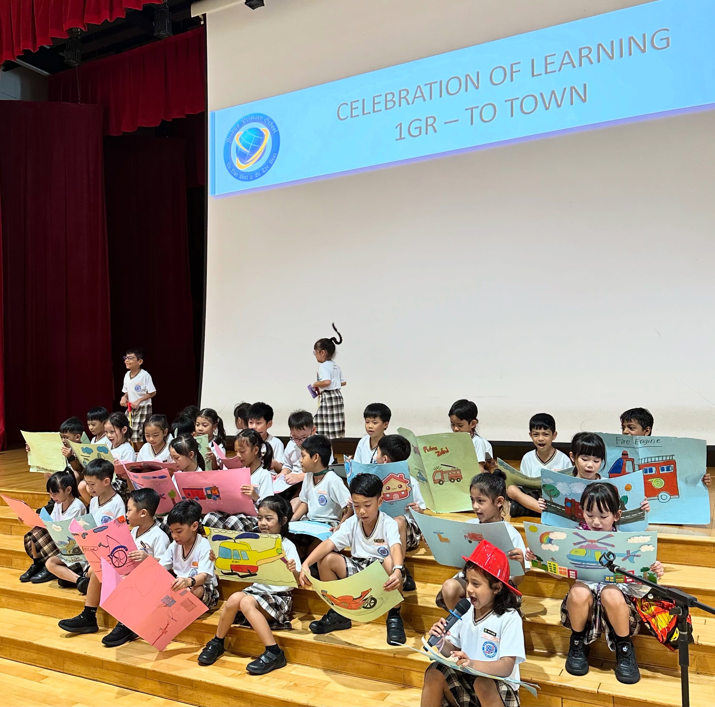 Students from 1 Gratitude showcasing artwork while performing "To Town" during Celebration of Learning.