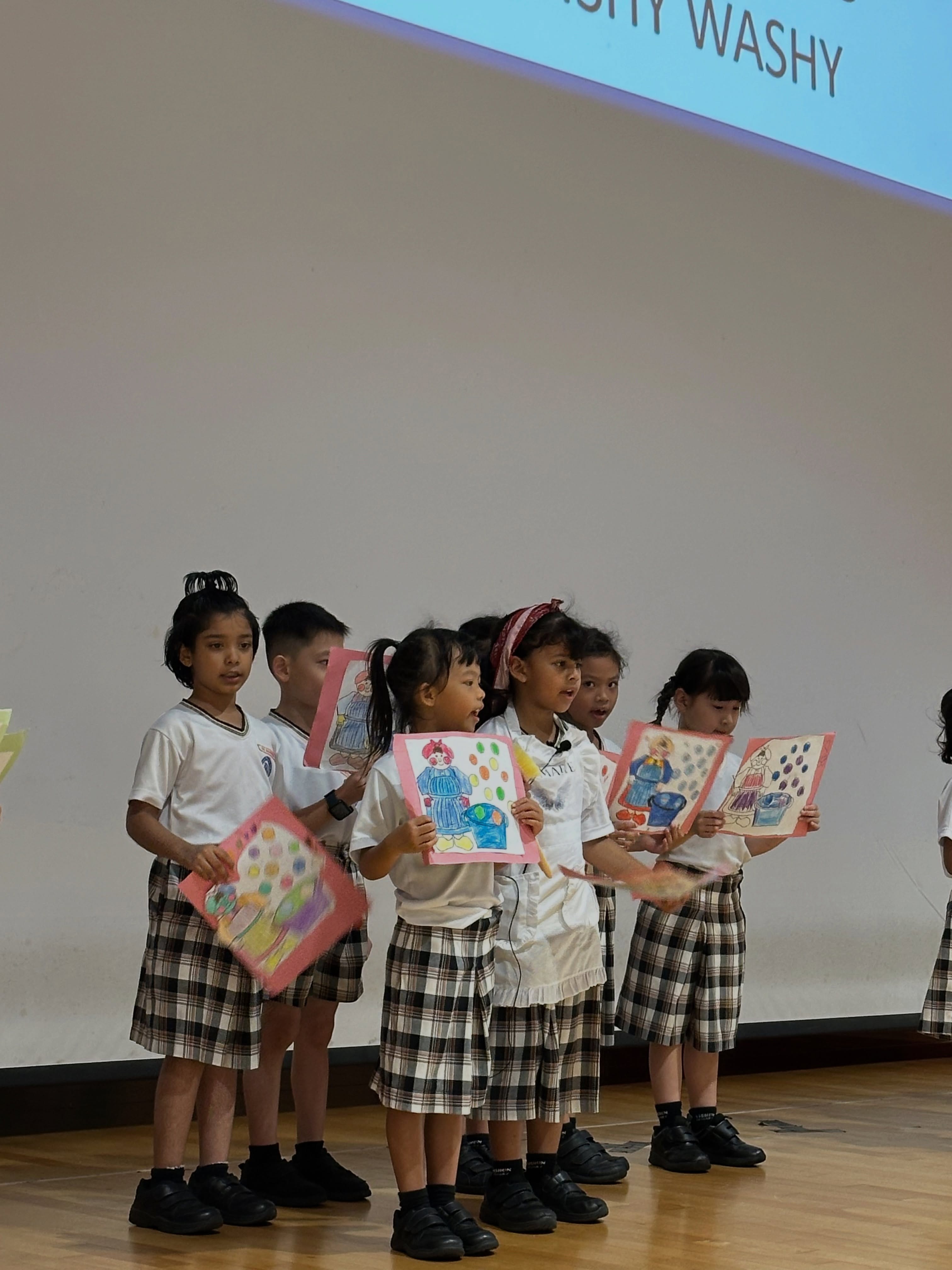 Students presenting artwork on stage during their Celebration of Learning performance.