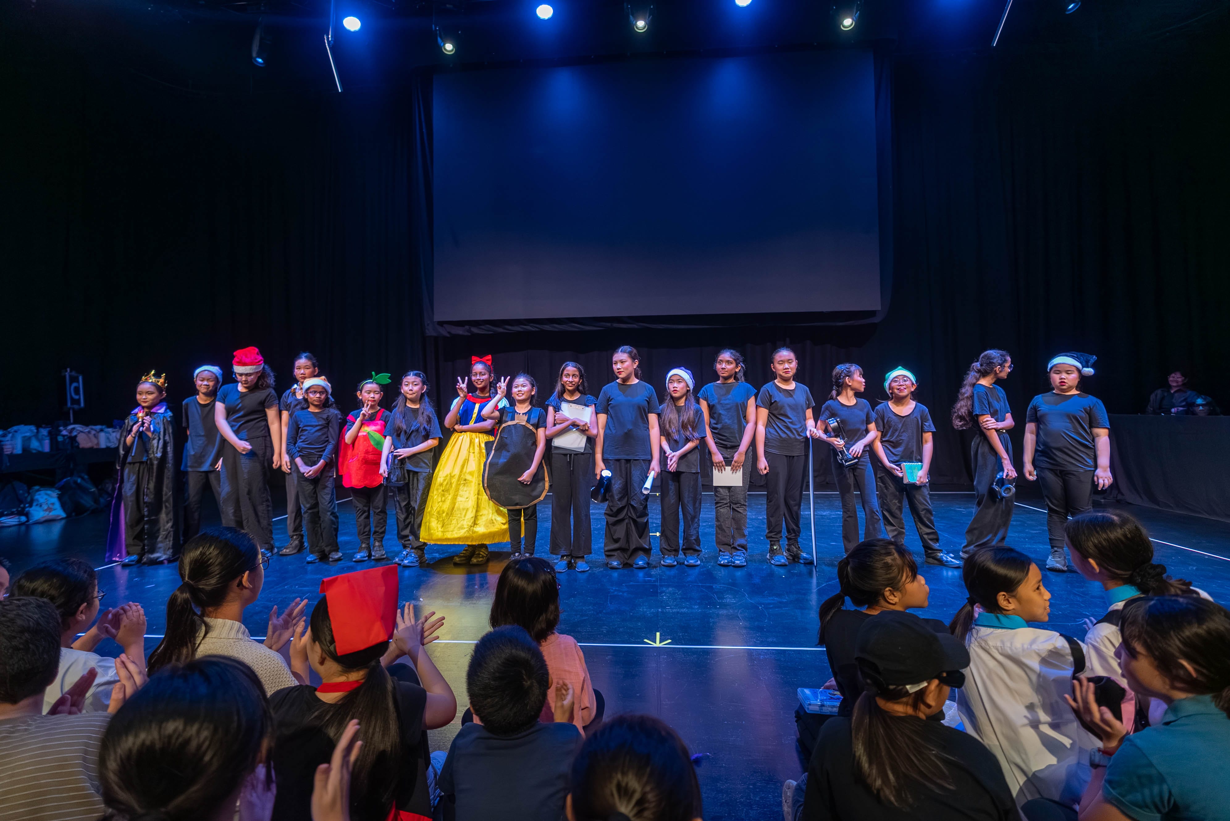 Students taking a bow after their drama performance as the audience applauds.