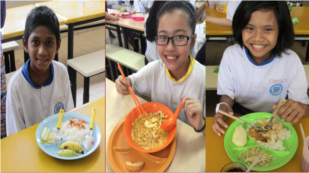 Three students smiling with their healthy set meals.