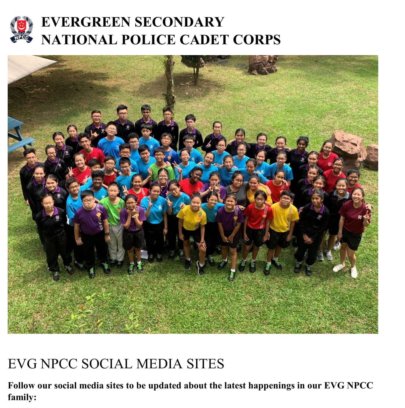 Large group of Evergreen Secondary NPCC students in colorful shirts posing outdoors on a grassy field.