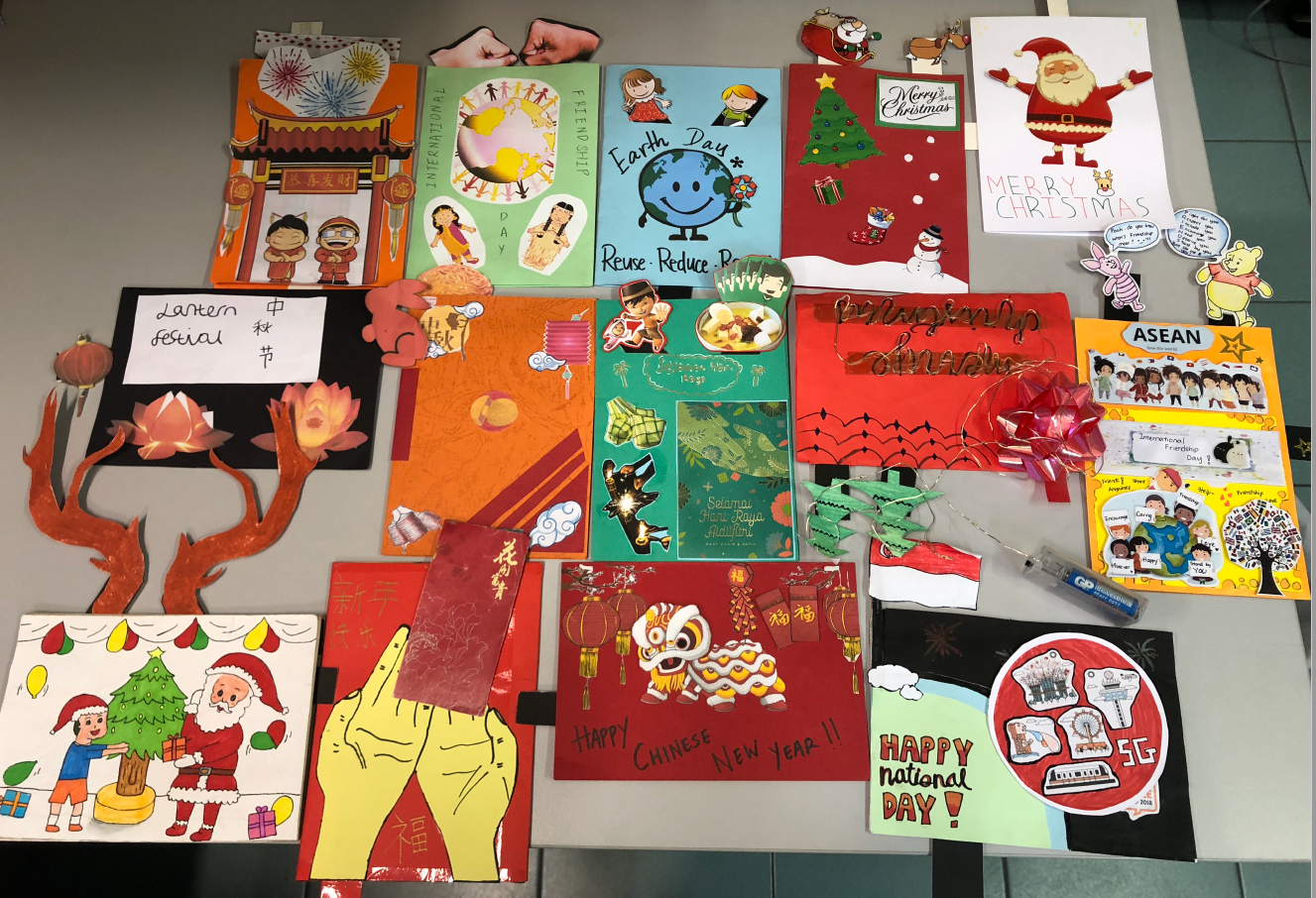 Colorful handmade posters on a table celebrating holidays like Christmas, Chinese New Year, Earth Day, and National Day.