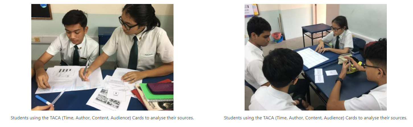 Students in school uniforms working together at desks, reviewing papers and cards as part of a classroom activity.