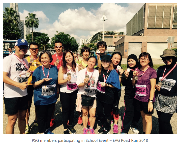 Group of runners wearing race bibs and medals posing outdoors after the EVG Road Run 2018.
