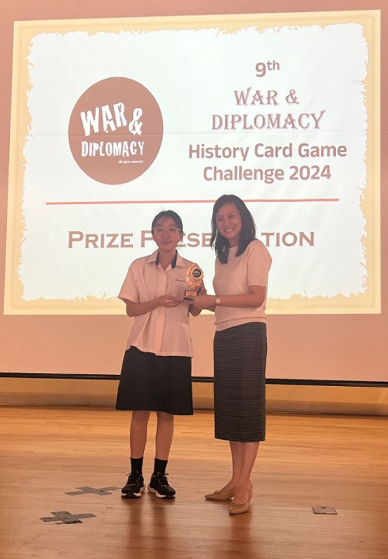 Two people hold a trophy at the 9th War and Diplomacy History Card Game Challenge 2024 prize presentation.
