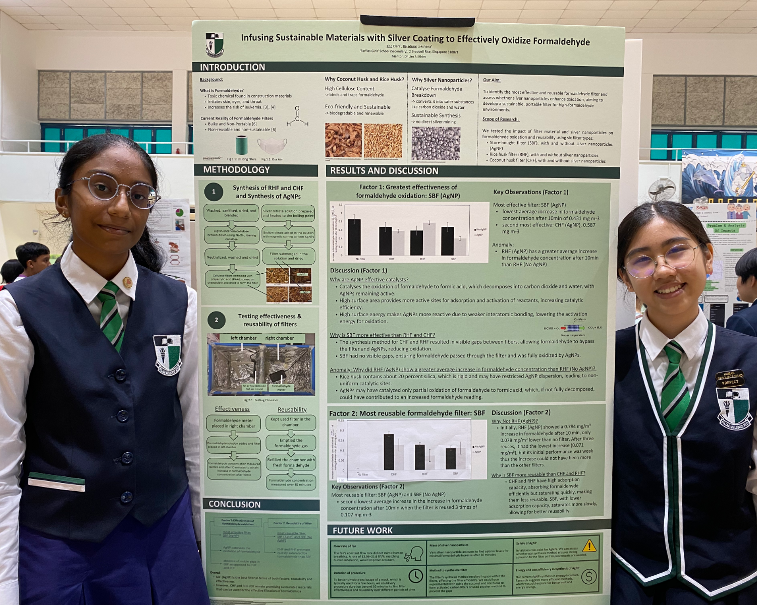 Two students in school uniforms stand beside a science research poster about infusing silver coating to oxidize formaldehyde.