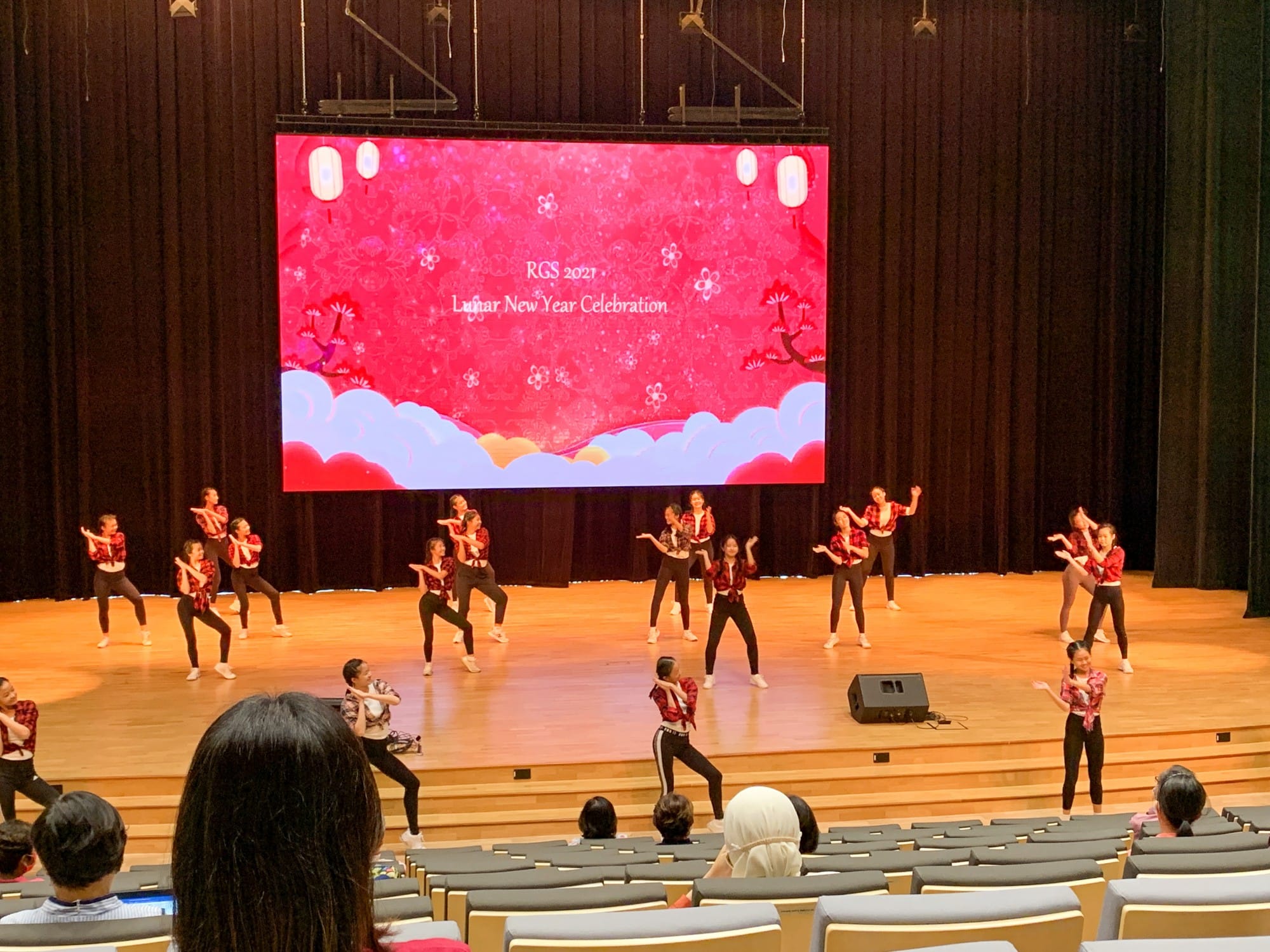 Students in red tops and black pants dance on a stage at RGS 2021 Lunar New Year Celebration.