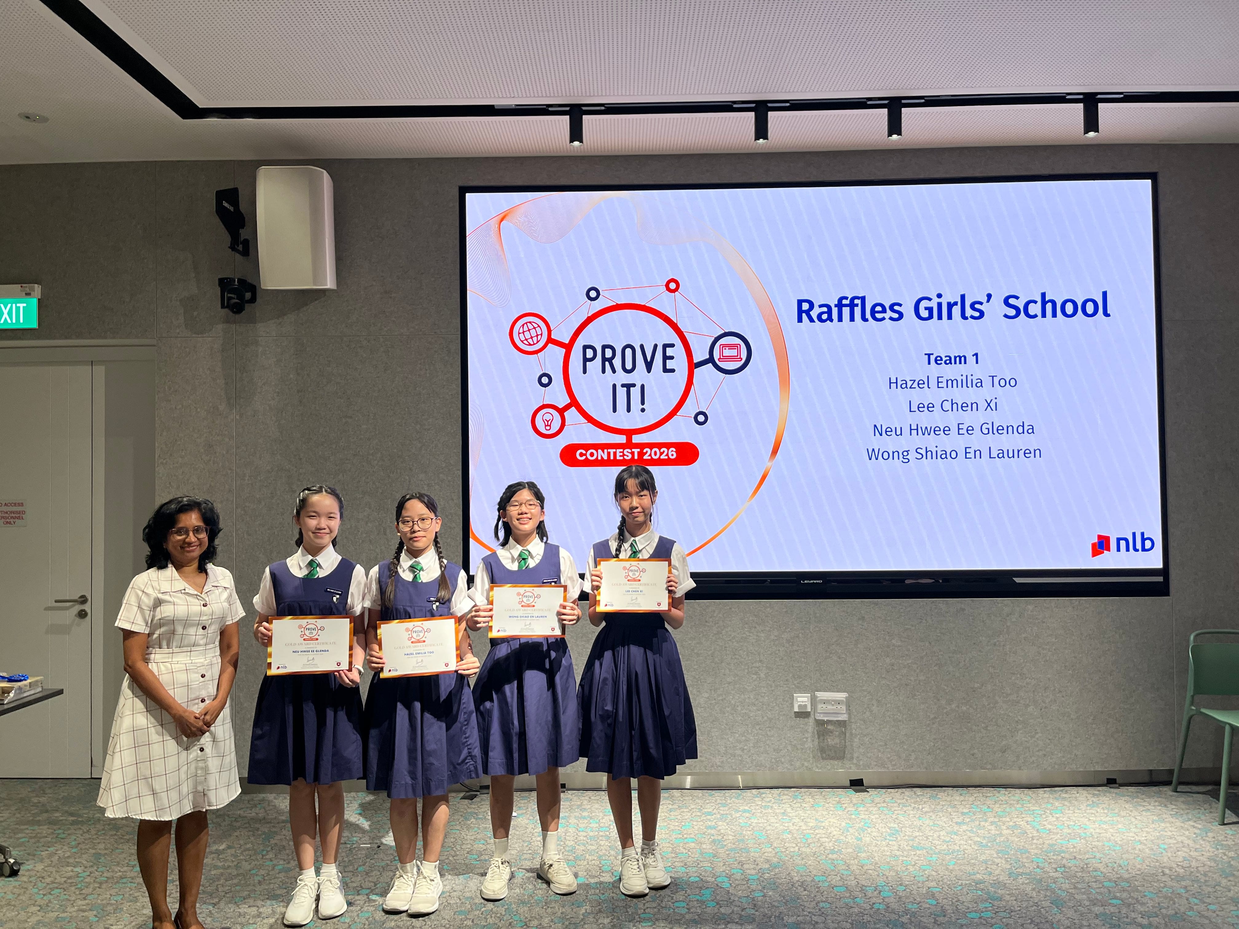A group photo of female students holding their award certificate and a female prize presenter, standing in front of a projected screen stating "Prove It! Contest 2026".
