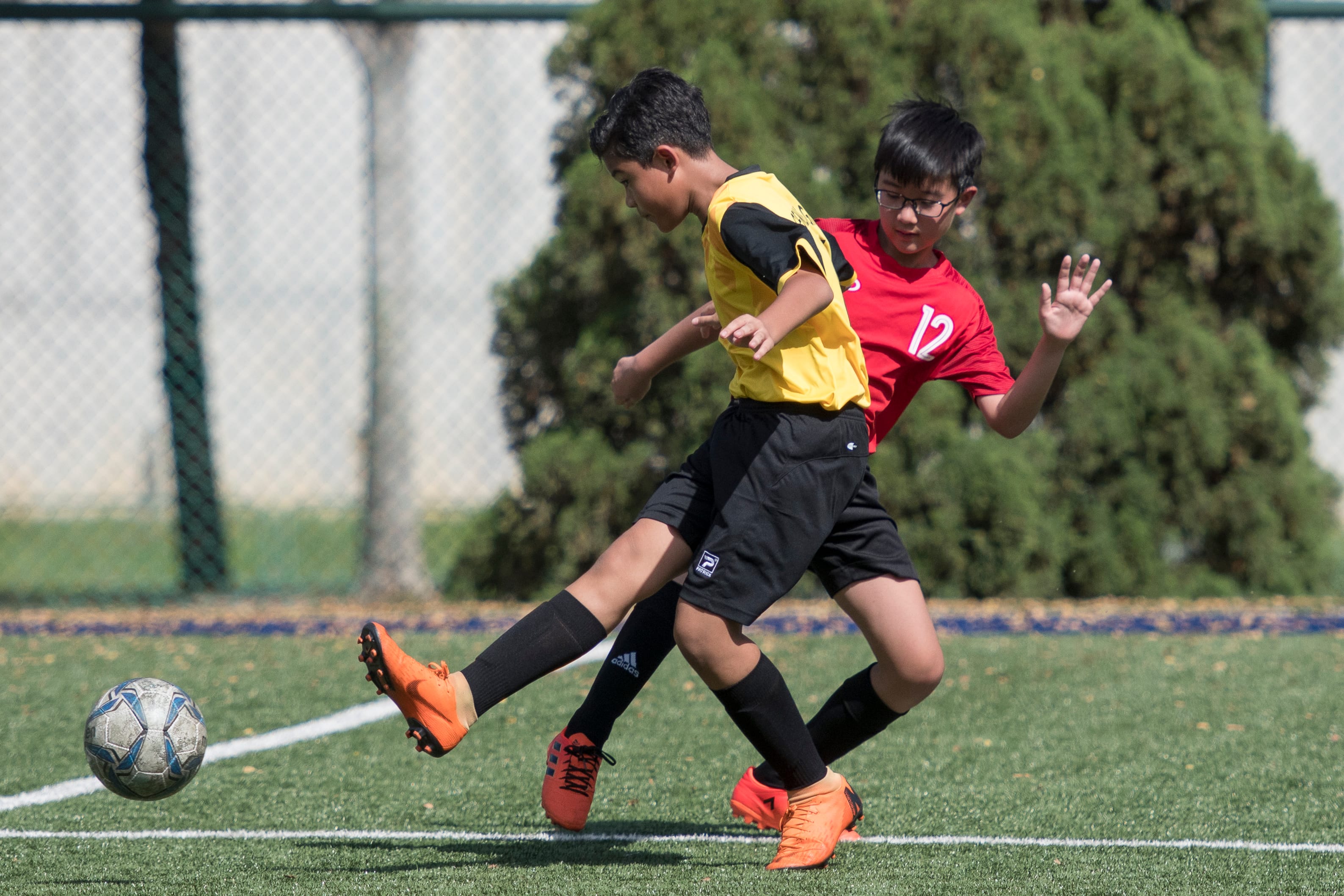 Our SKG boys playing soccer on a green turf field.