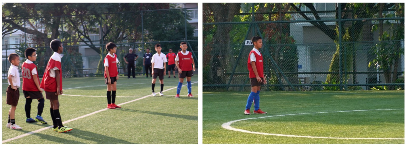 Young boys in red soccer vests stand on a green turf field during a youth football session.