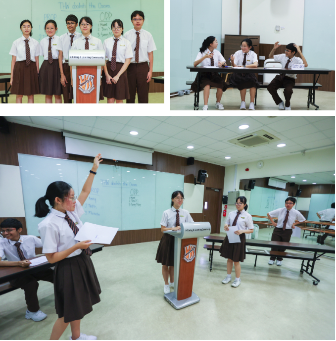 Students in white and brown uniforms participate in a debate, with one speaking at a podium and others standing nearby.
