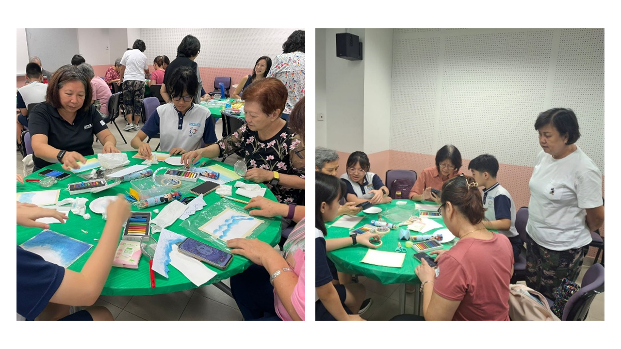 Groups of people sit around green-covered round tables doing an art craft activity with pastels and paper.