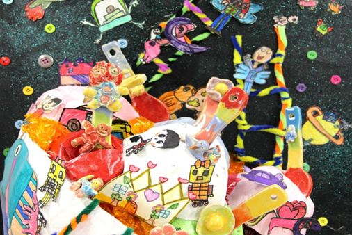 Colorful children's art collage with toys, drawings, buttons, and figurines on a dark background.