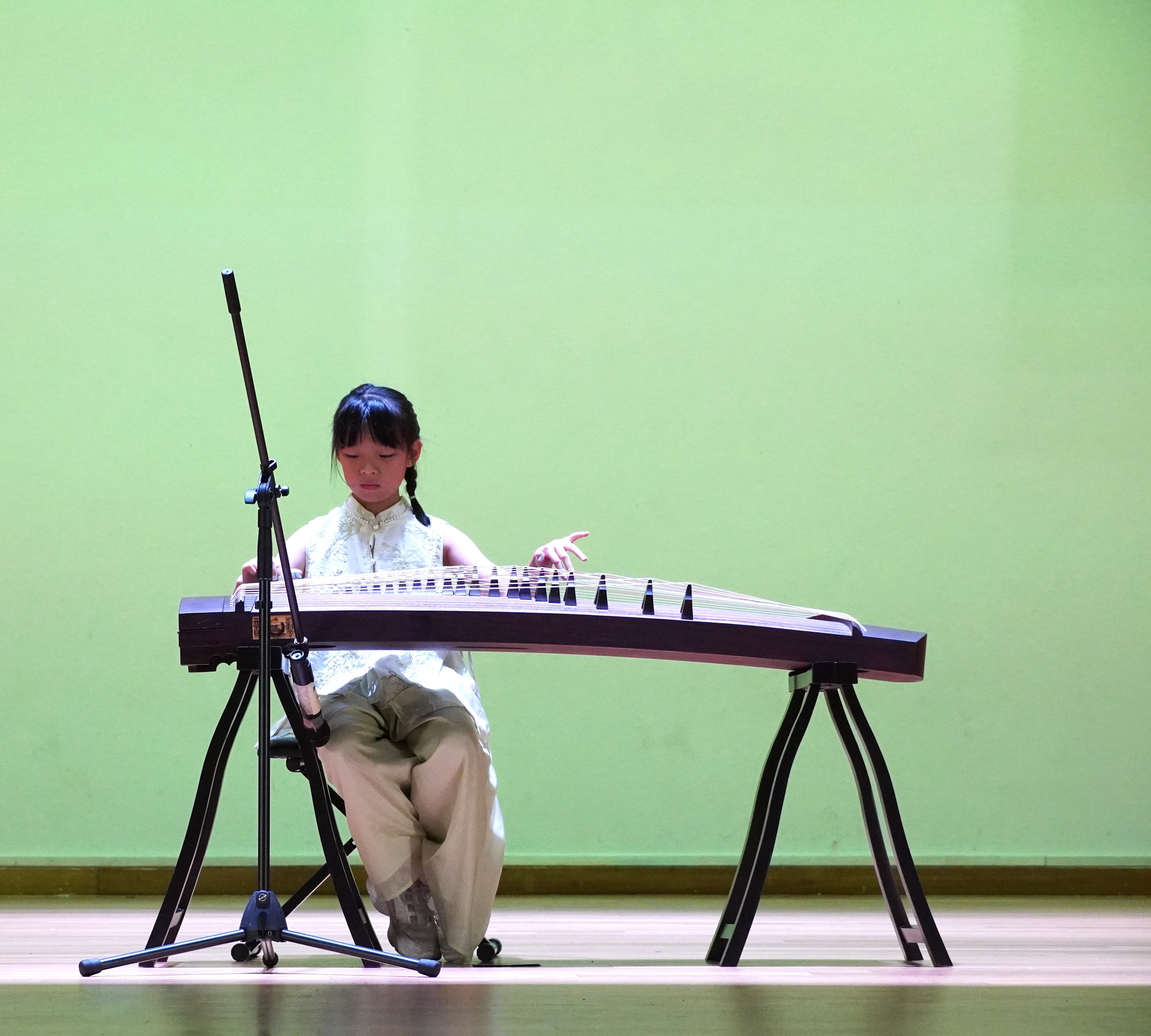 Student playing a traditional Chinese musical instrument on stage.