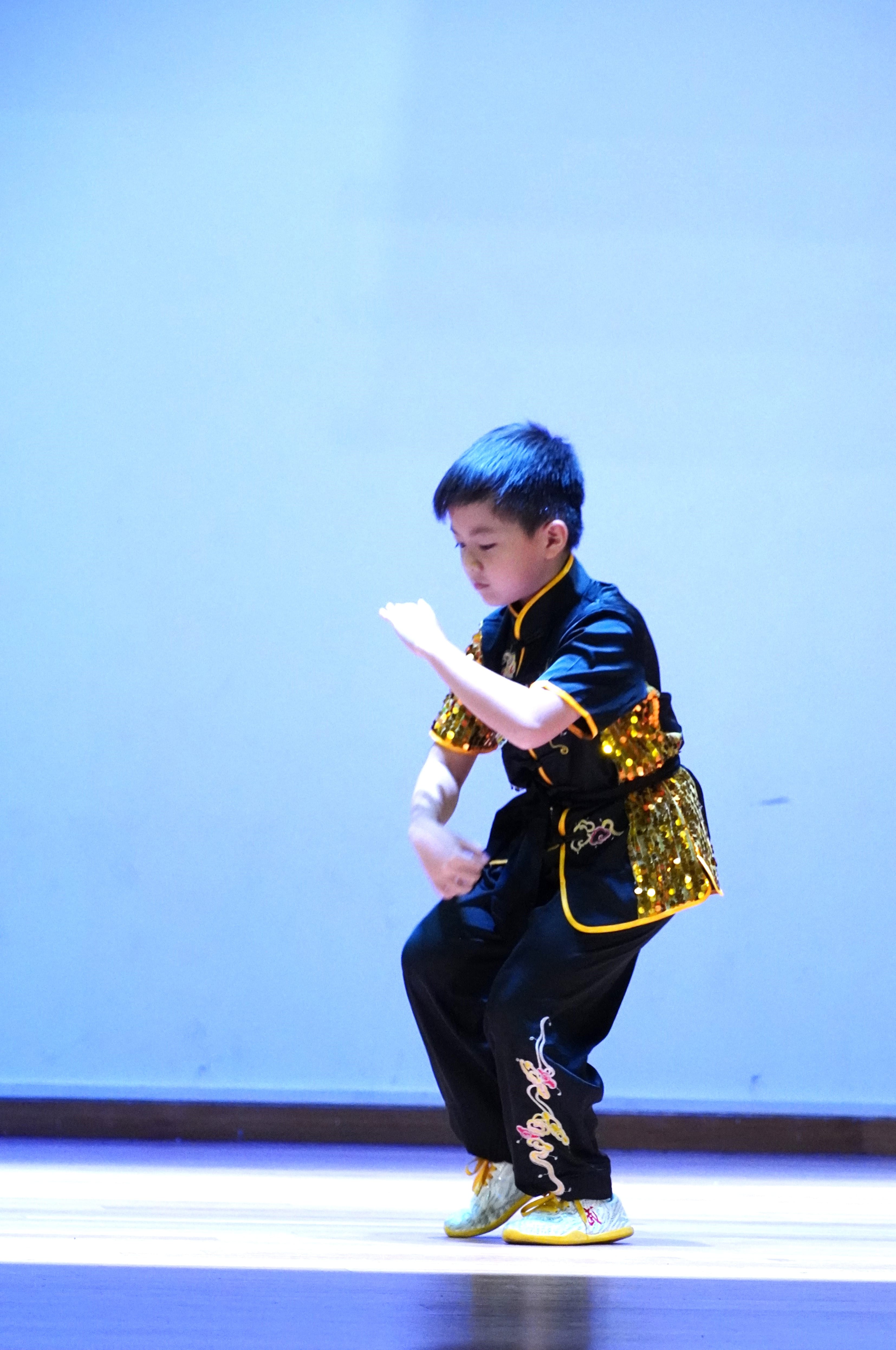Student performing a traditional martial arts routine on stage.