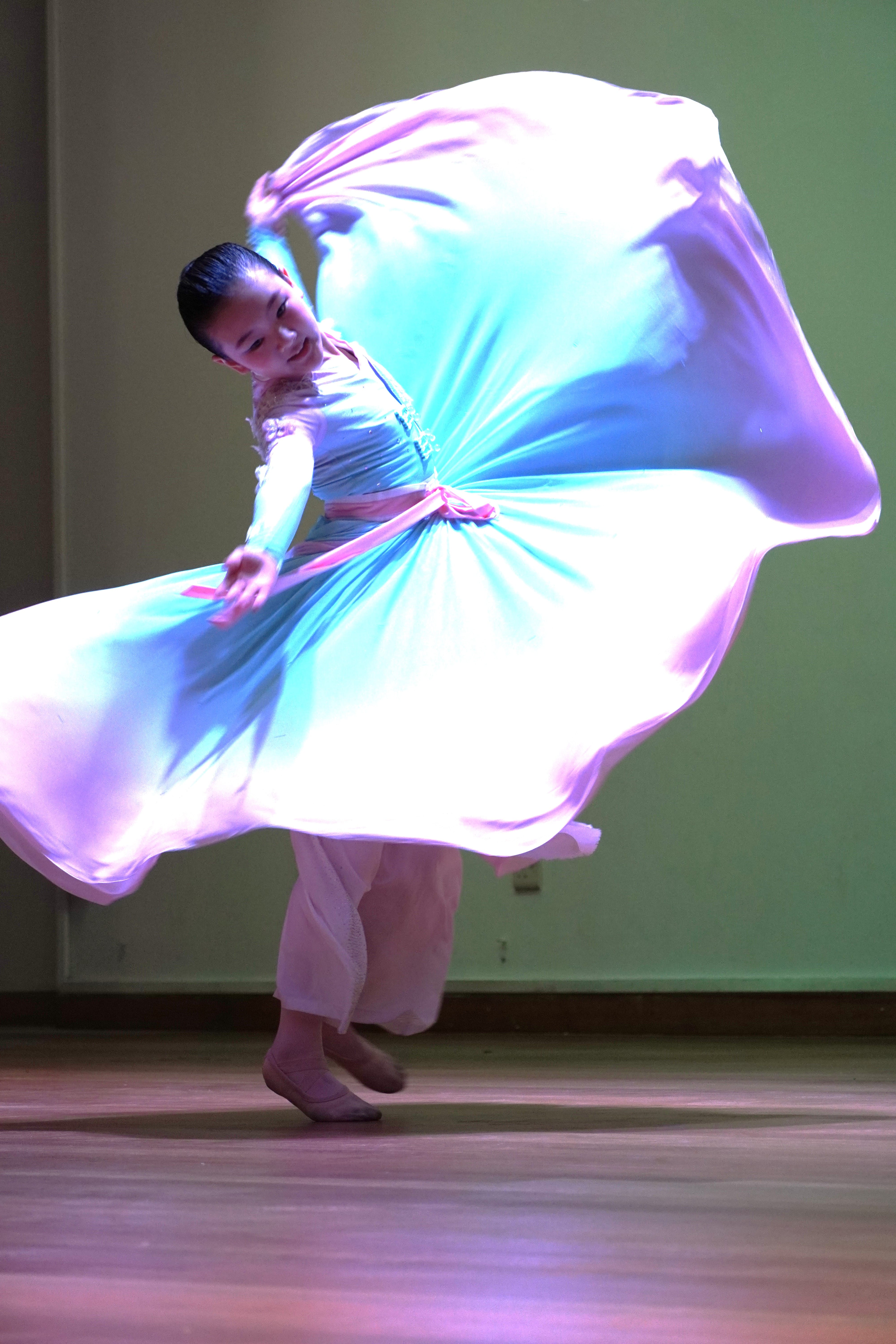 Student performing a colourful traditional dance with a flowing costume.