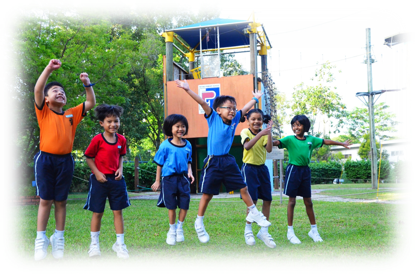 Six cheerful children in colorful school uniforms jump and pose on grass near a playground structure.