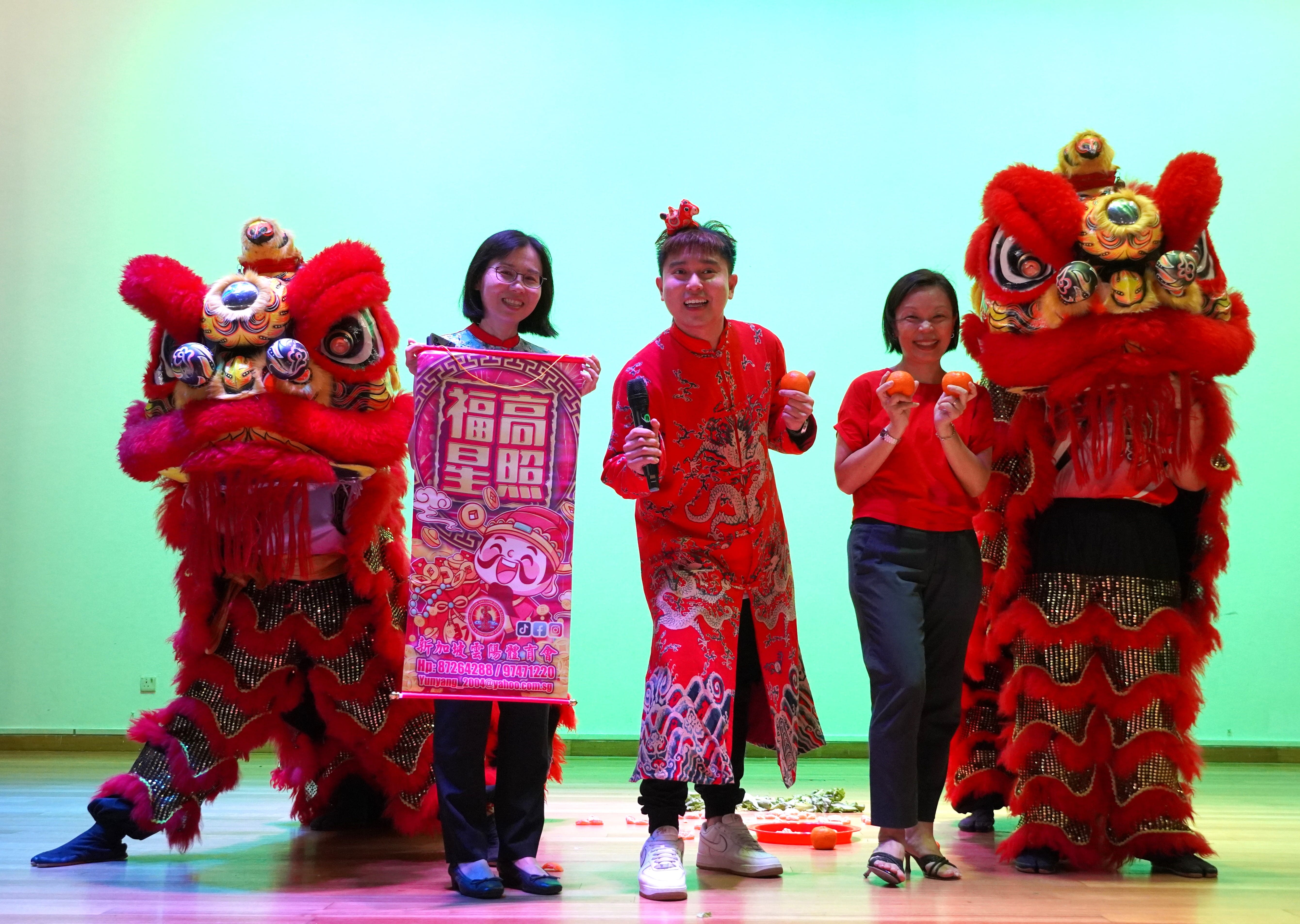 School staff taking picture with Chinese lion dance on stage.