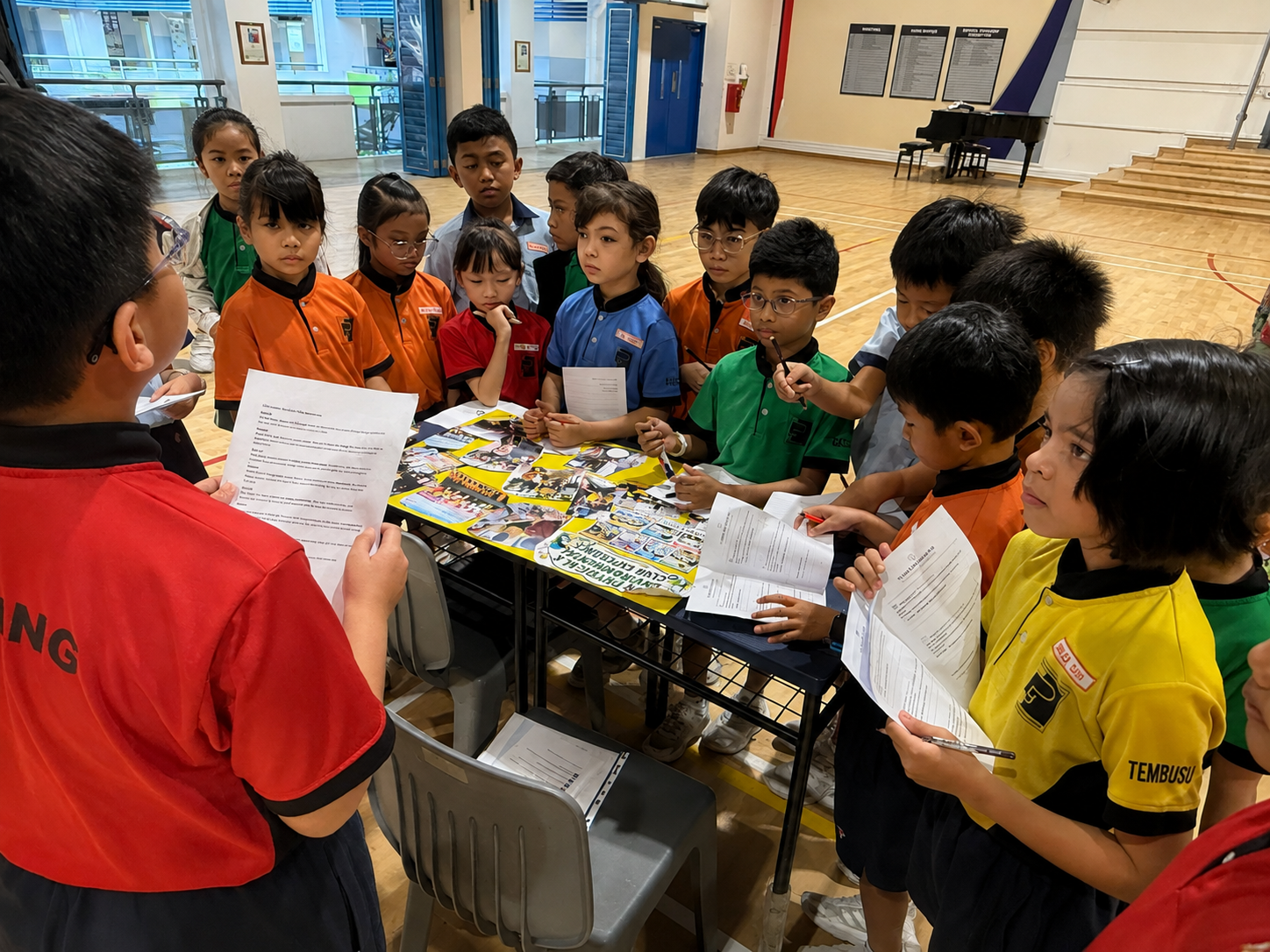 A student leader sharing information with Primary 2 students during a school activity.