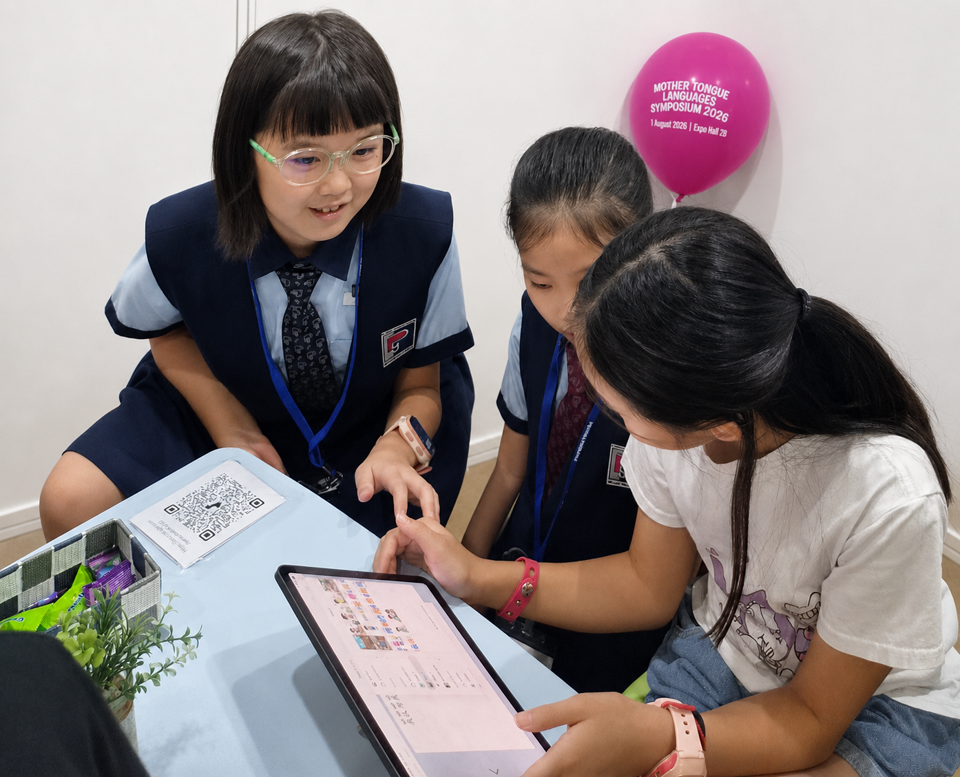Three primary school students in uniform looking at a tablet together at a table.