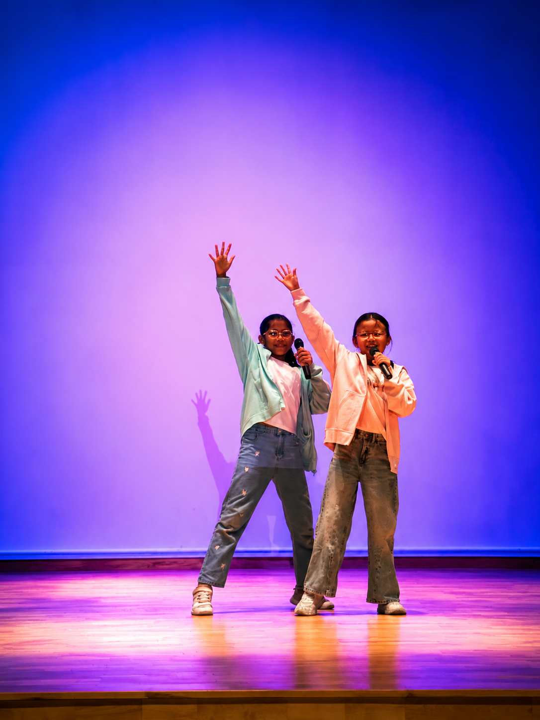 Students striking a celebratory pose on stage.