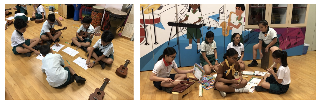 Children in uniforms sit on a floor with ukuleles and a xylophone during a school music activity.