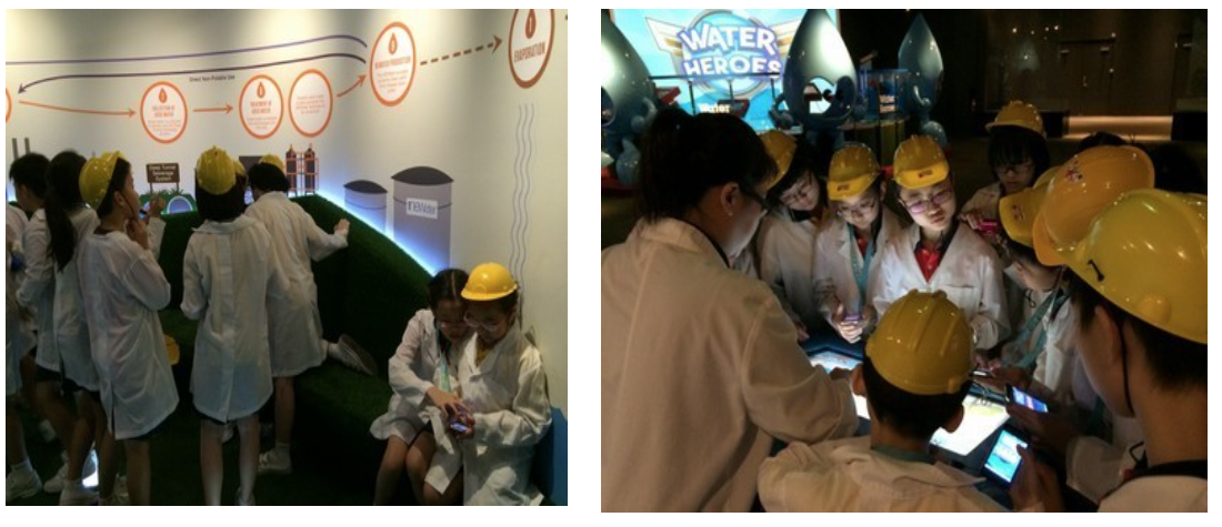 Children in yellow hard hats and white lab coats explore a water-themed educational exhibit called Water Heroes.